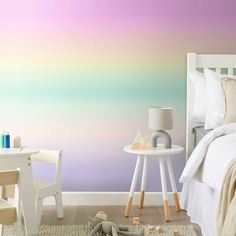 a room with a bed, table and chair in front of a wall painted with pastel colors