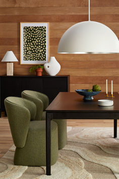 a dining room table with green chairs and a white lamp hanging over it's head