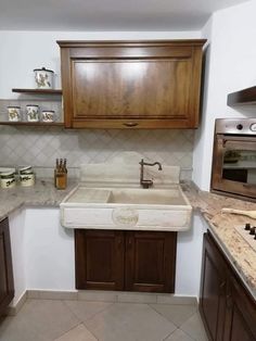 a kitchen with wooden cabinets and marble counter tops, including a white farmhouse style sink