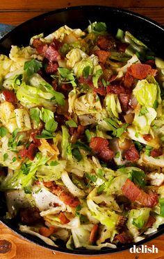 a skillet filled with lots of food on top of a wooden table