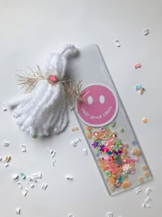 a bookmark with some confetti on it and a tassel attached to it