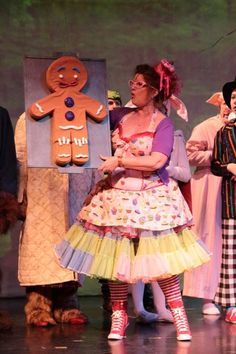 a group of people standing on top of a stage next to each other wearing costumes