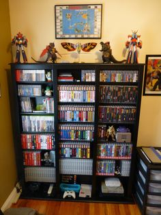 a bookshelf filled with lots of dvds and video game equipment in a living room