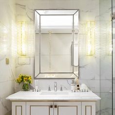 a bathroom with a sink, mirror and flowers in the vase on the counter top