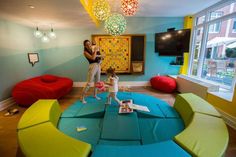 a woman and her dog standing in the middle of a living room with brightly colored furniture