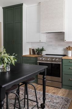 a kitchen with green cabinets and an island in front of the stove top, along with a rug on the floor