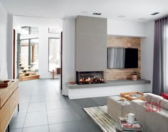 a living room with a couch, fireplace and television on the wall in front of it