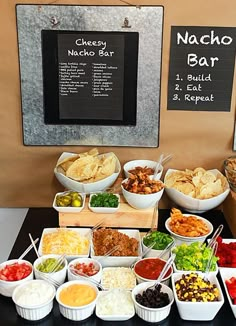 a table filled with lots of different types of food and drinks next to a chalk board