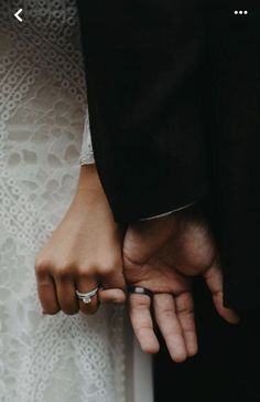 two people are holding hands and wearing wedding rings