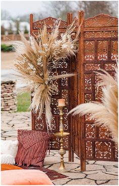 an outdoor ceremony with tall pamodia and candlesticks on the ground in front of it