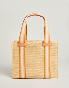 The Charlie Tote: made with soft faux straw, striped in bold webbing and trimmed in top grain Napa leather. With natural colors made to seamlessly work into your everyday style and an easy-to-reach back pocket, this tote will be your most-loved accessory. Summer Handwoven Straw Tote Bag, Beachy Woven Straw Tote Bag, Handwoven Top Handle Beach Bag, Beachy Handwoven Straw Tote Bag, Beach Straw Tote Bag With Gold-tone Hardware, Back Pocket, Natural Colors, Everyday Style, Cotton Weaving