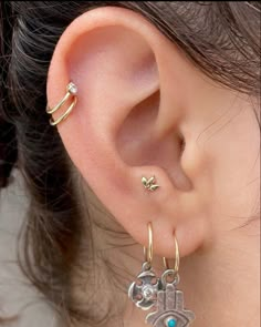 an ear with two small charms attached to it's sides and one has a hamsa hand