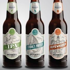 three beer bottles with labels on them sitting side by side in front of a gray background