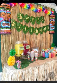 a table topped with lots of food next to a tiki mask wall hanging from the ceiling