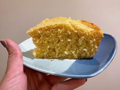 a piece of cake on a plate being held by a woman's hand,