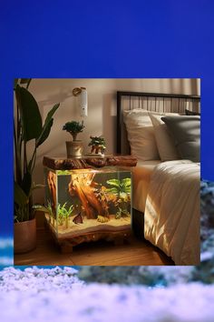 a fish tank sitting on top of a table next to a bed