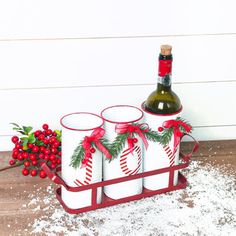 a wine bottle and four cups in a sled with holly wreaths on it