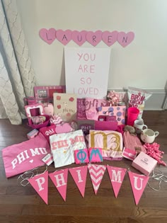 pink and gold birthday party decorations on wooden floor next to sign that says you are so loved