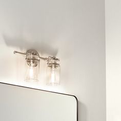 two mason jar lights on the wall above a mirror