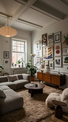 a living room filled with furniture and lots of pictures on the wall above it's windows