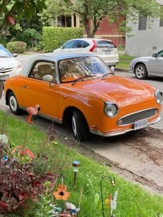 an orange car is parked on the side of the road in front of some cars