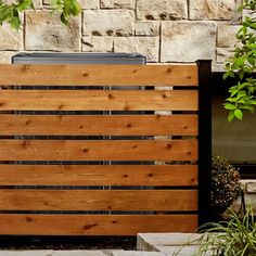 a wooden fence next to a brick wall and potted planter in front of it