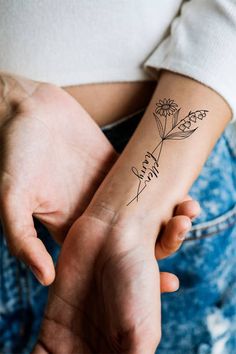 a woman's arm with a tattoo on it that says faith and daisies