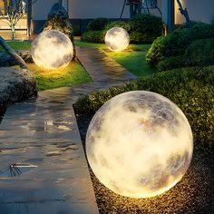 two large white balls sitting on top of a lush green field next to a walkway