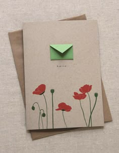 a card with an envelope on top of it and some red flowers in the middle