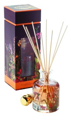 reed diffuser in glass container next to box with flowers and butterflies on the inside