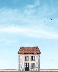 a small house sitting in the middle of a field with a bird flying over it