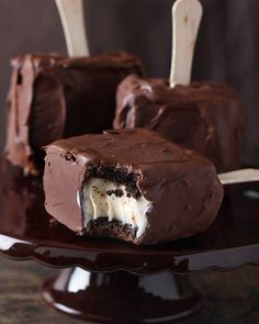 two pieces of chocolate covered ice cream on a plate with wooden spoons in it