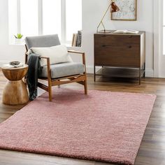 a living room with a pink rug and chair