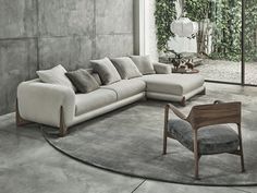 a living room with a large sectional couch and chair in the middle, surrounded by greenery