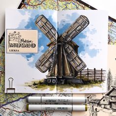 an open book with a drawing of a windmill on it and some markers next to it