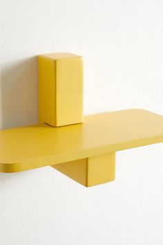 a yellow shelf sitting on top of a white wall