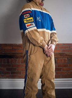 Vintage 1970s Pyrotect Racing Suit | Third Coast Racing | Men's XL This rare 1970s/80s vintage Pyrotect racing suit is in beautiful vintage quality. A durable cotton, this item features a velcro closure at collar, front zip, two side pockets, and a belt with velcro closure. A very comfortable fit with lots of stretch. Third Coast Racing logo embroidery on chest and back, and a variety of racing patches across arms. Brown/khaki colour, blue with white detail stripes across mid section and down si Vintage Race Jacket, Racing Bodysuit, Racing Patches, Ski Racing Suit, Vintage Racing Jacket, Racing Logo, Khaki Colour