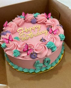 a birthday cake with pink frosting and butterflies on it in a cardboard box that says happy birthday