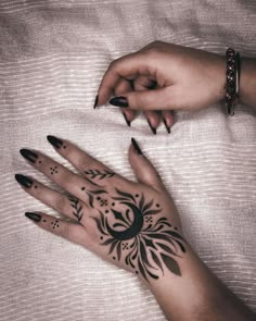 a woman's hand with black and white tattoos on it, next to her left hand