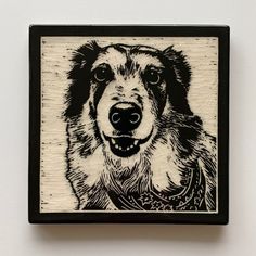 a black and white drawing of a dog's face on a wood block,