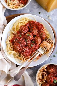 two bowls of spaghetti with meatballs and parmesan cheese on the side next to bread