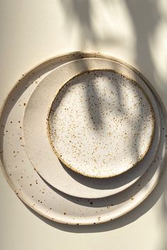 two white plates with gold speckles are sitting on a table next to each other