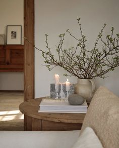 two candles are lit on a table next to a vase with some branches in it