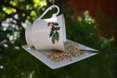 a bird feeder hanging from the side of a tree with holly decorations and berries on it