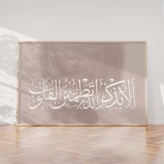 an arabic calligraphy is displayed on the wall in front of a wooden floor and white walls