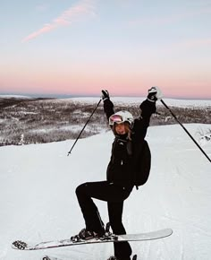 a woman riding skis on top of a snow covered slope with her arms in the air