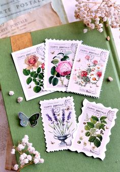 four stamps with flowers and butterflies on them sitting next to each other in front of a book