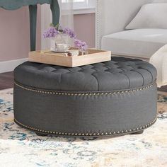 a round ottoman sits on top of a rug