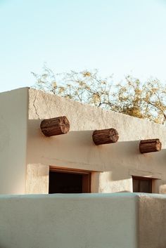 an adobe building with three wooden barrels on the roof