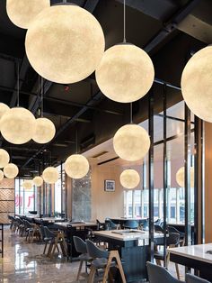 an empty restaurant with tables and chairs, lights hanging from the ceiling in front of them